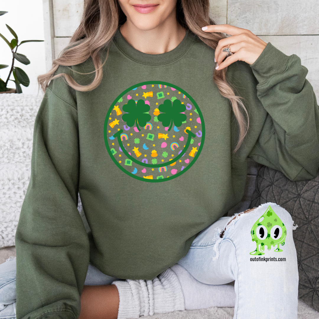A person wearing a green sweatshirt with a smiley face design made of clovers and multicolored elements on the front.