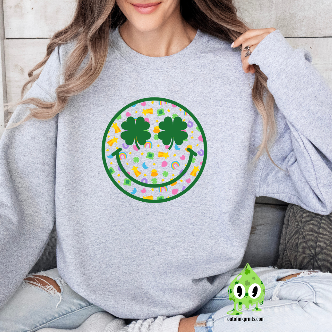 A person wearing a gray sweatshirt with a smiley face design made of clovers and multicolored elements on the front.