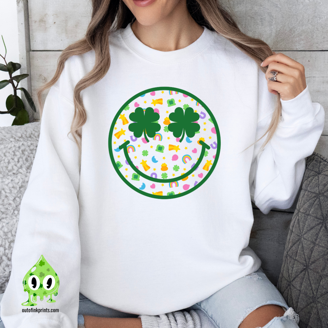 A person wearing a white sweatshirt with a smiley face design made of clovers and multicolored elements on the front.