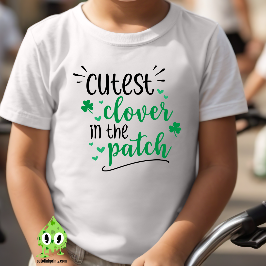 Child wearing a white t-shirt with the text 'CUTEST CLOVER IN THE PATCH' and small clover leaves, in a outdoor setting.
