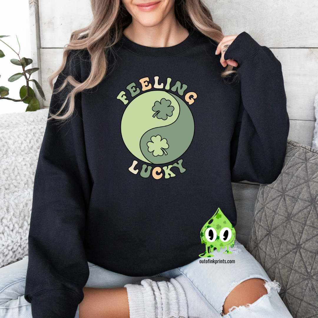 A woman wearing a black sweatshirt with 'Feeling Lucky Yin & Yang' text and a four-leaf clover, in a yin and yang design.