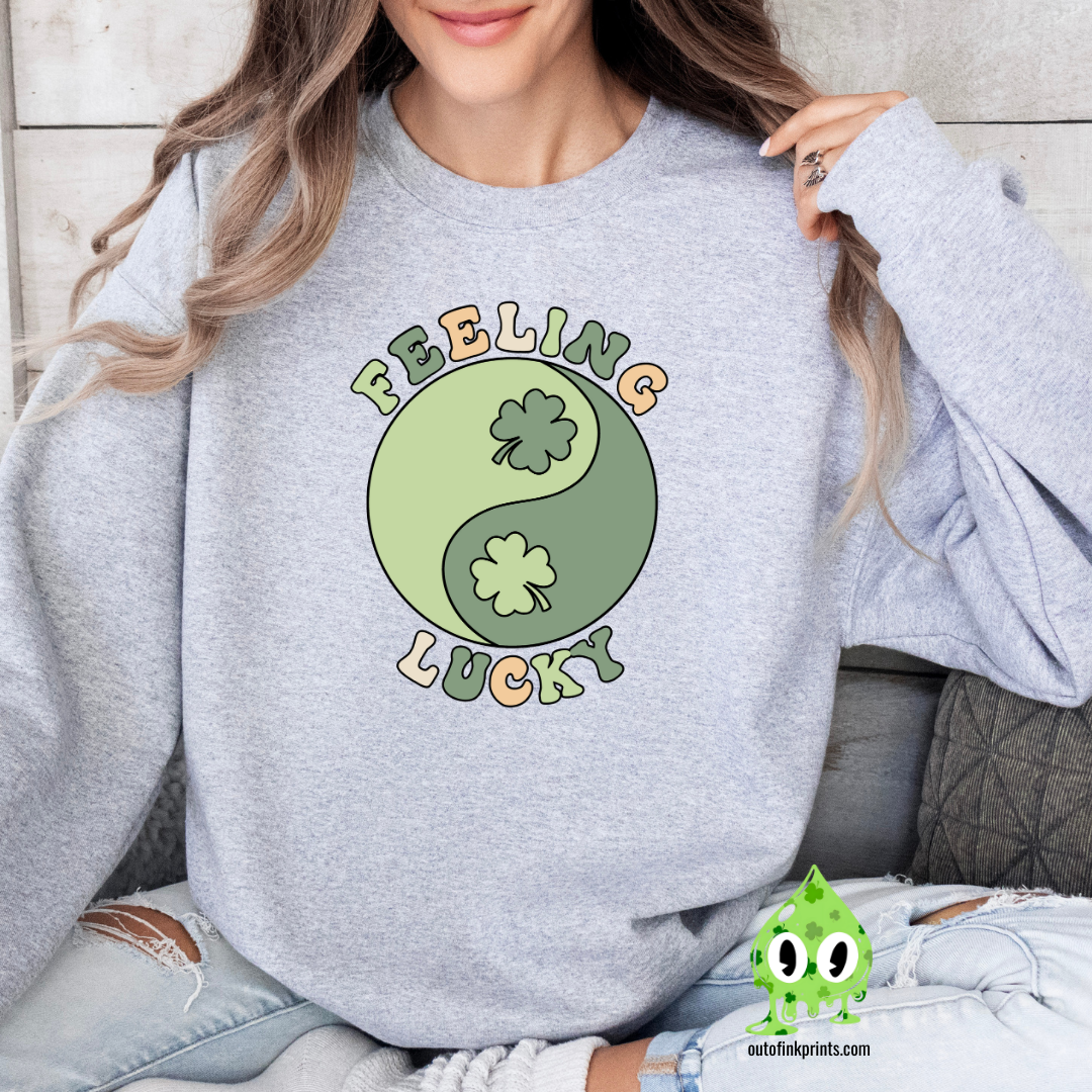 A woman wearing a grey sweatshirt with 'Feeling Lucky Yin & Yang' text and a four-leaf clover, in a yin and yang design.