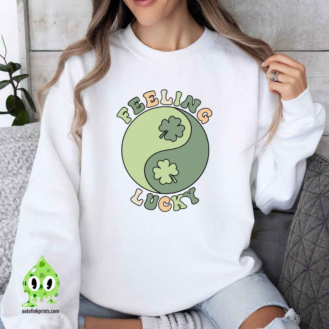 A woman wearing a white sweatshirt with 'Feeling Lucky Yin & Yang' text and a four-leaf clover, in a yin and yang design.