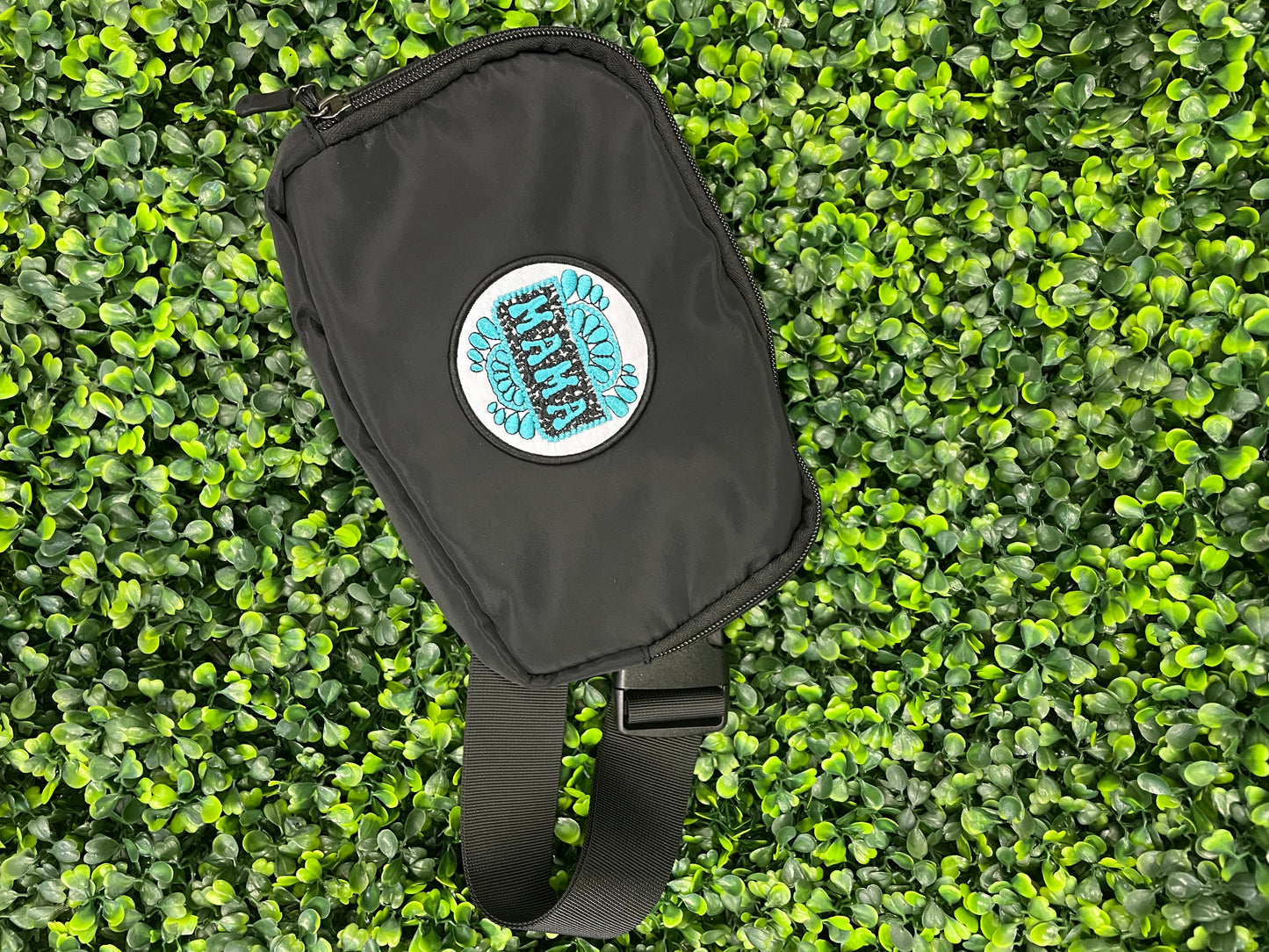 Circular patch with 'MAMA' text placed onto a black shoulder bag