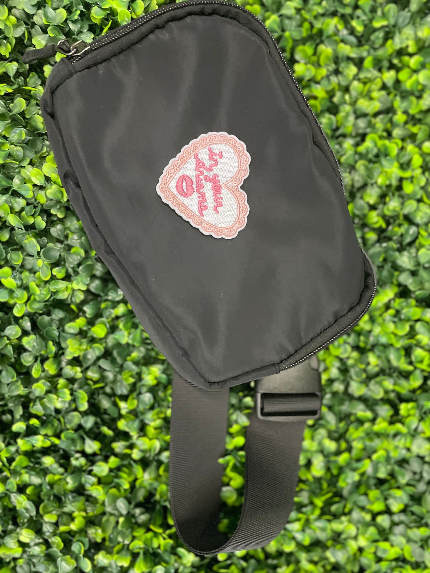 Heart-shaped embroidered patch with 'In your dreams' text held against a black shoulder bag
