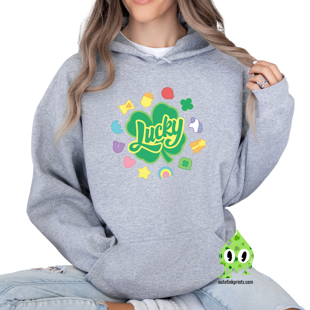 A gray hoodie with a 'Lucky Marshmallows' graphic in green, featuring clovers and other St. Patrick's Day themed elements.
