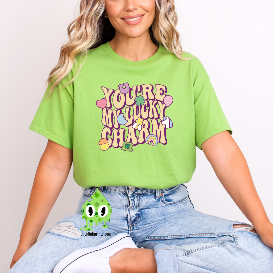 Front view of a green t-shirt with the text 'YOU'RE MY LUCKY CHARM' in a playful font, surrounded by decorative elements like shamrocks and hearts.