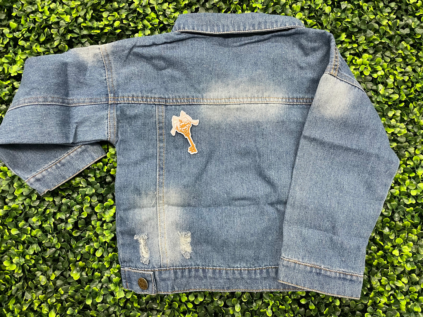 A patch in the shape of a vintage key with a gold bow, embroidery work, set on a jean jacket