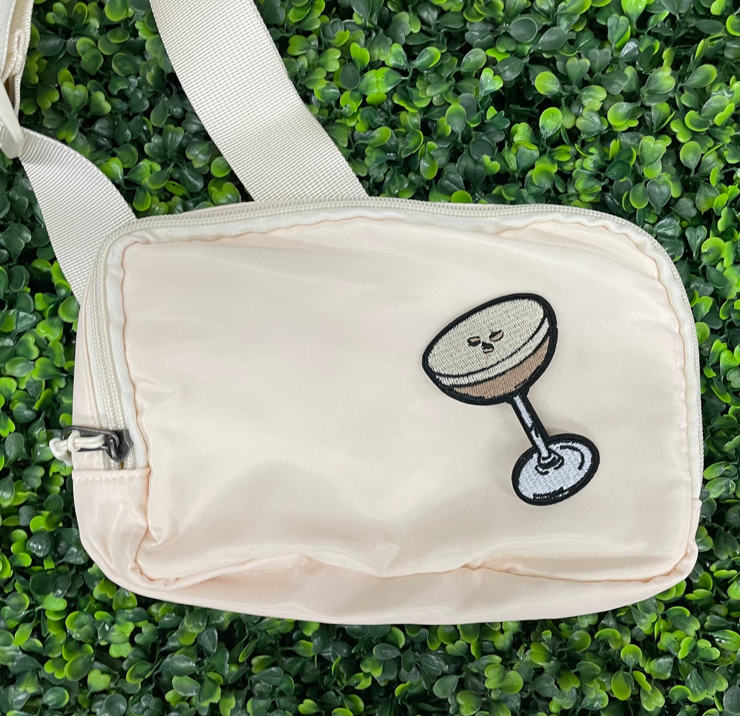 An iron on embroidered martini glass depiction set on a white shoulder bag