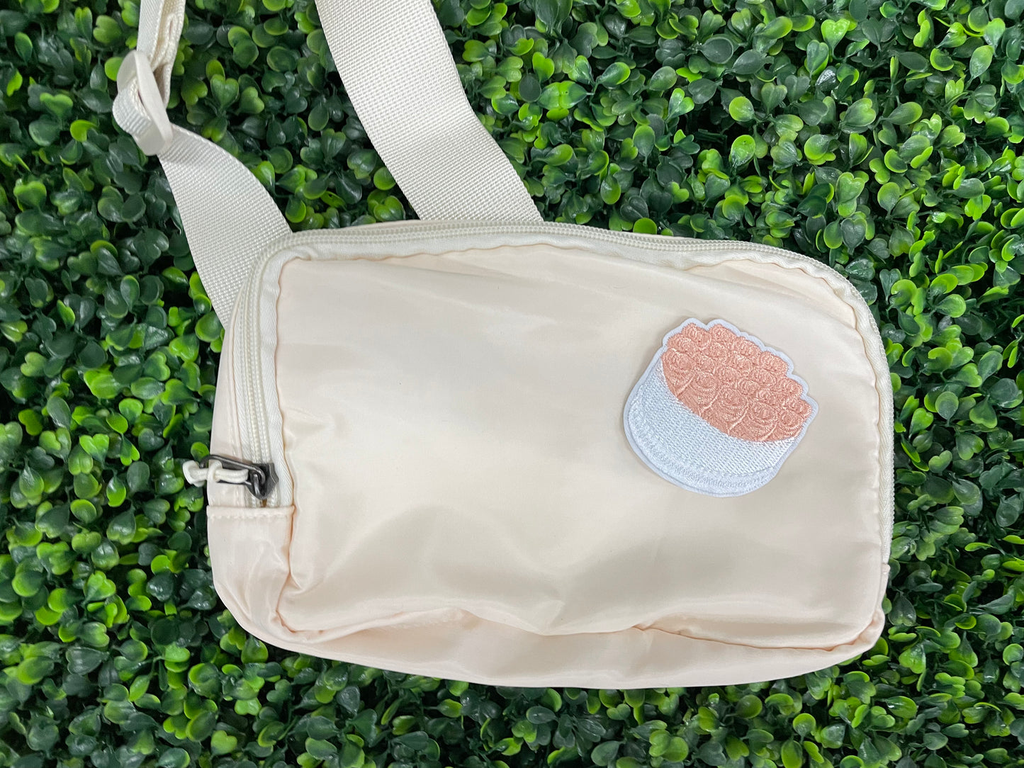 An embroidered patch in the shape of a bundle of roses with pink petals and green leaves, placed on a white bag
