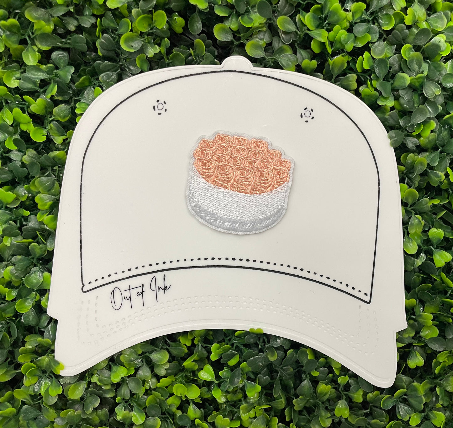 An embroidered patch in the shape of a bundle of roses with pink petals and green leaves, placed on a white hat