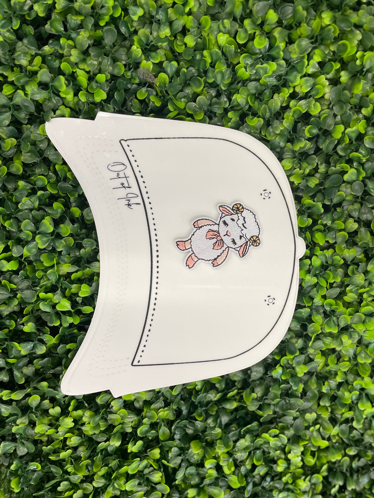 Patch of a cartoon lamb held against a white trucker hat graphic