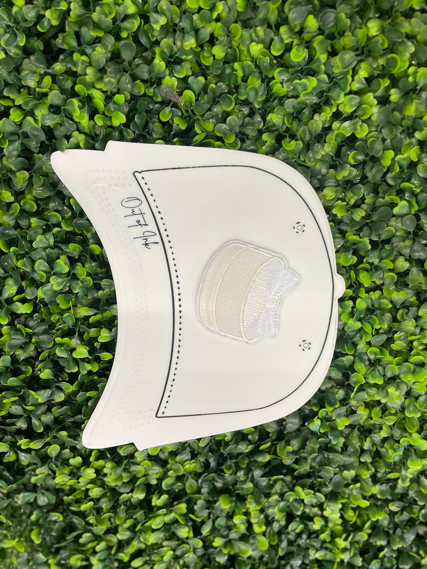 Embroidered patch of a white cake with a white bow placed on top, placed on a white trucker hat graphic