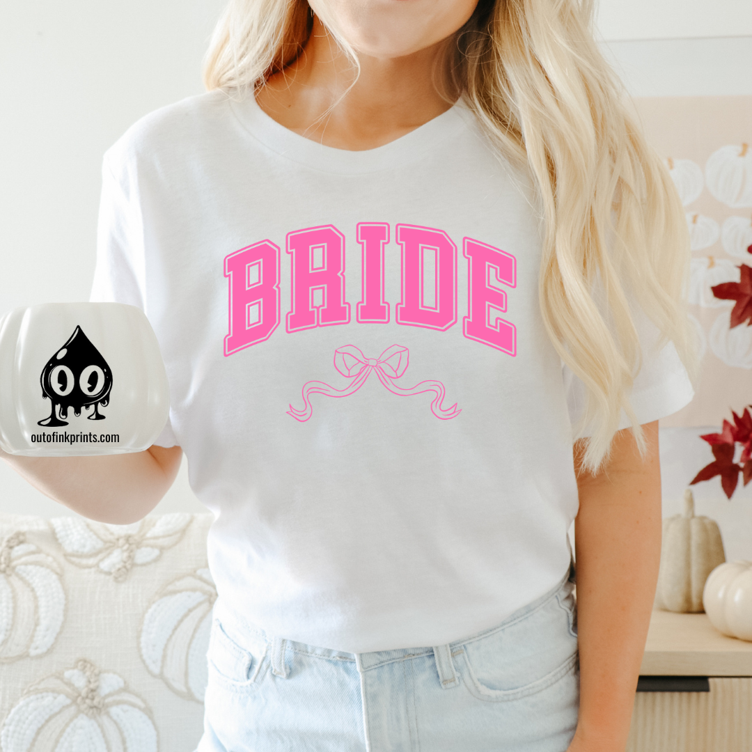 Front view of a white t-shirt with the word 'Bride' and a pink bow graphic on it.