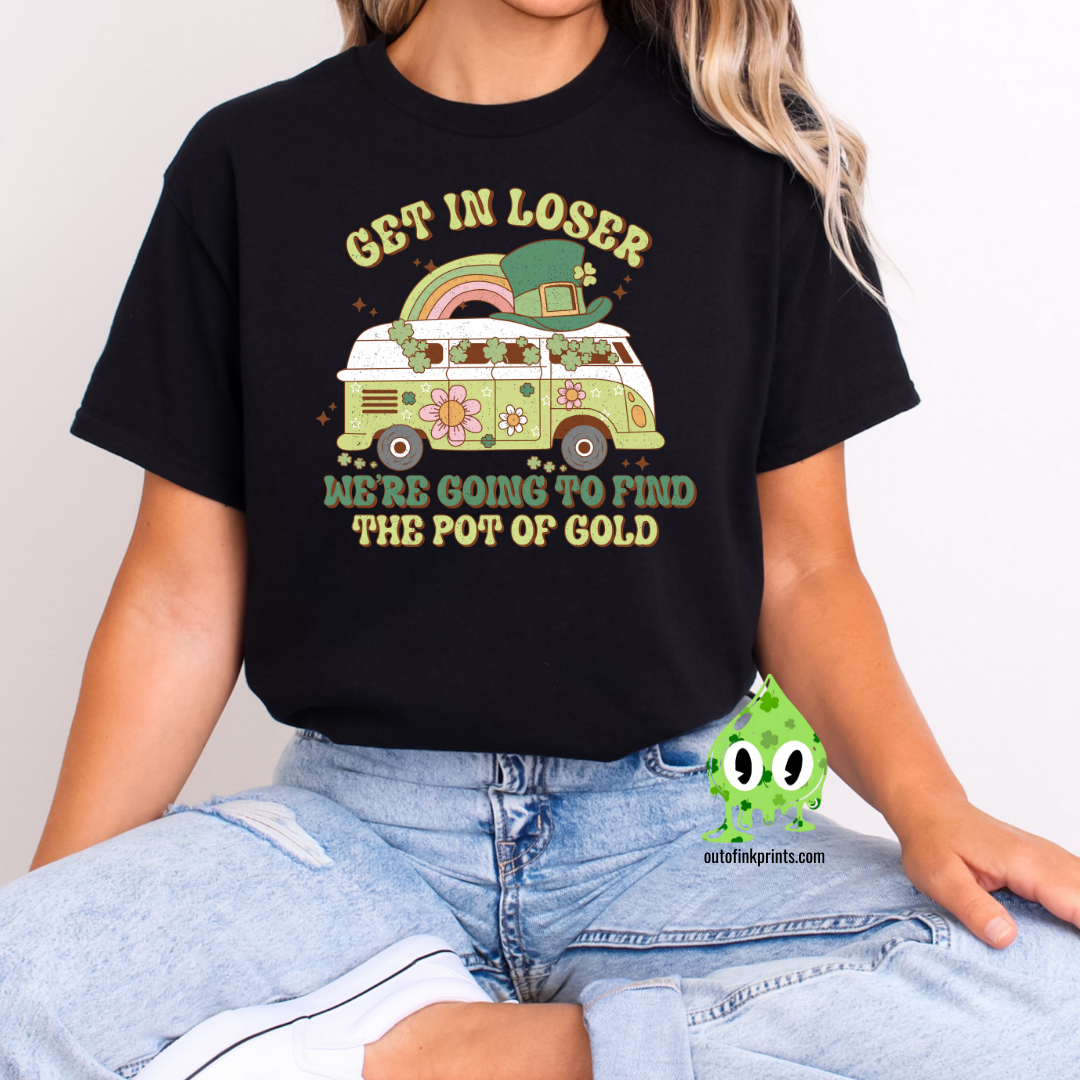 A woman wearing a black t-shirt with the text 'GET IN LOSER ST. PATRICK'S' and a graphic of a pot of gold and a leprechaun.
