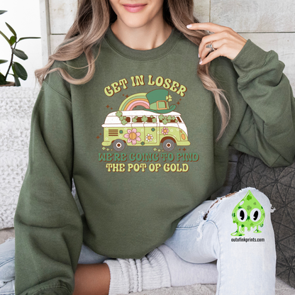 A woman wearing a green sweatshirt with a St. Patrick's Day theme, featuring text and a graphic of a rainbow, clover, and what appears to be a leprechaun.