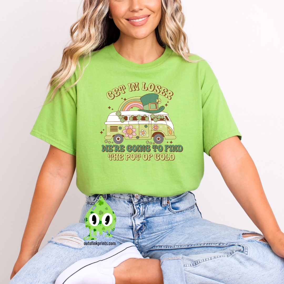 A woman wearing a light green t-shirt with the text 'GET IN LOSER ST. PATRICK'S' and a graphic of a pot of gold and a leprechaun.