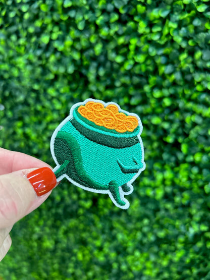 Green cauldron embroidered patch filled with gold coins and white border.