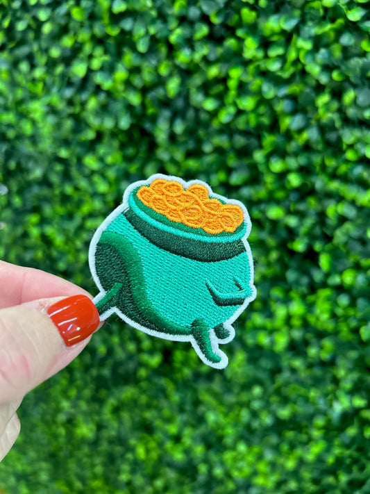 Green cauldron embroidered patch filled with gold coins and white border.