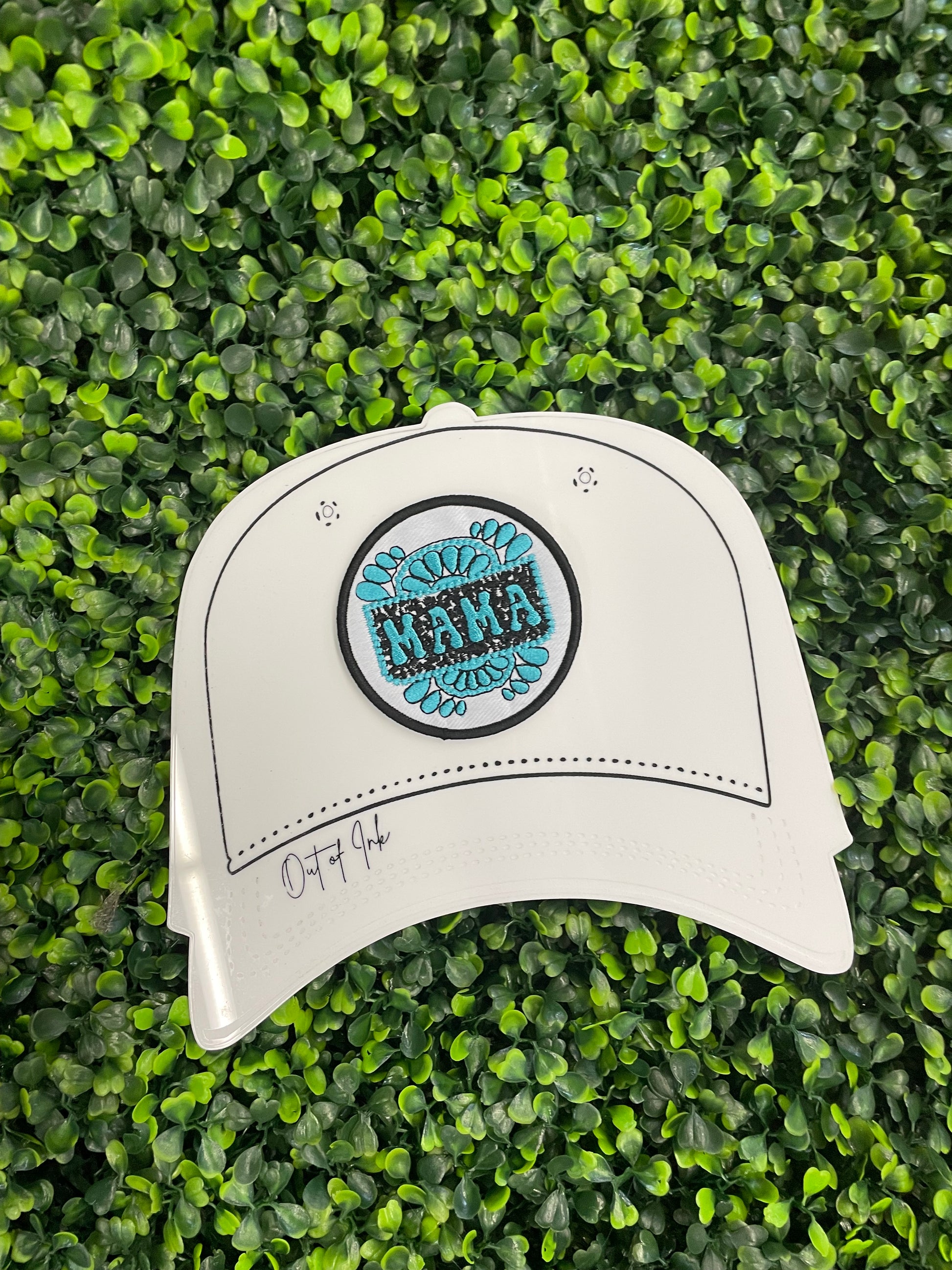 Circular patch with 'MAMA' text placed on a white trucker hat graphic