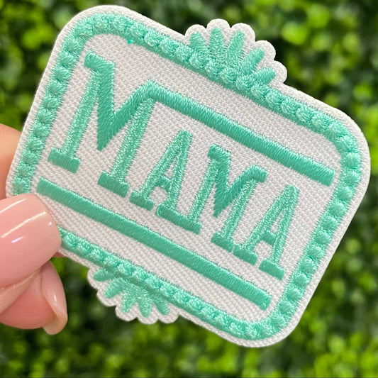 Patch with 'MAMA' text held against a green leafy background