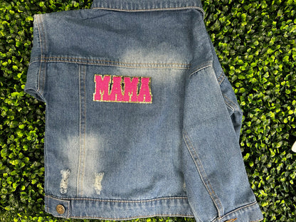 Blue denim jacket with pink text patch on a grass background