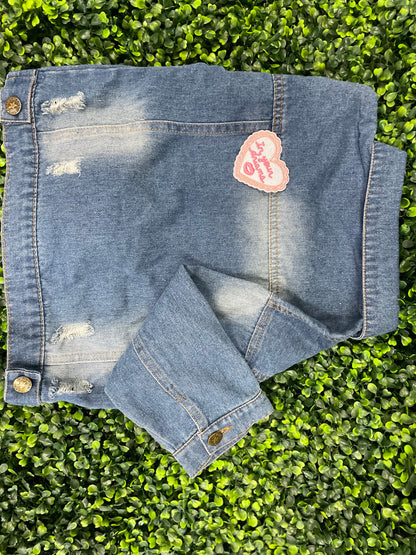 Heart-shaped embroidered patch with 'In your dreams' text held against a children's denim jean jacket
