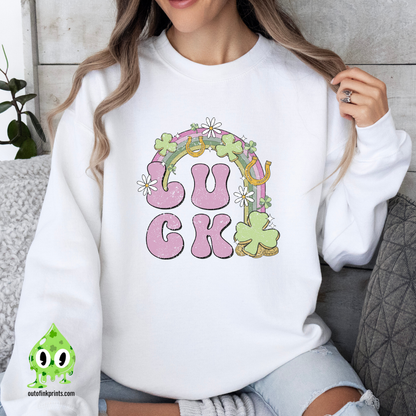 A woman wearing a white sweatshirt with the text 'LUCK' arranged in a playful design using Irish-themed graphics such as shamrocks and a four-leaf clover.