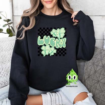 A woman wearing a black sweatshirt with a checkered pattern and a design that includes the text 'LUCKY' and shamrock shapes in a lighter green.