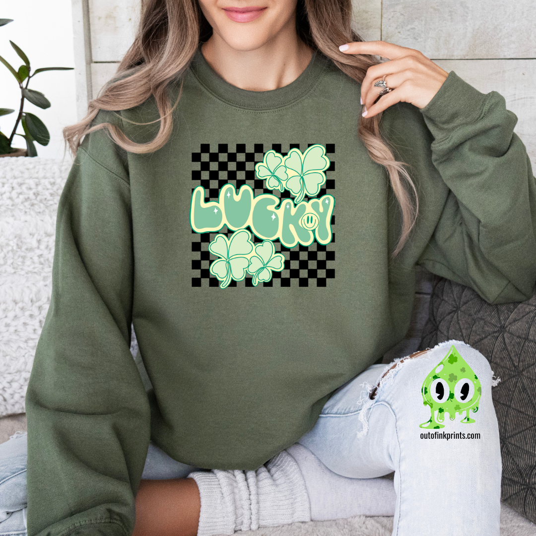 A woman wearing a green sweatshirt with a checkered pattern and a design that includes the text 'LUCKY' and shamrock shapes in a lighter green.