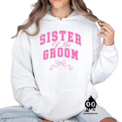 A woman wearing a white hoodie with 'Sister of the Groom' text and a pink bow design.
