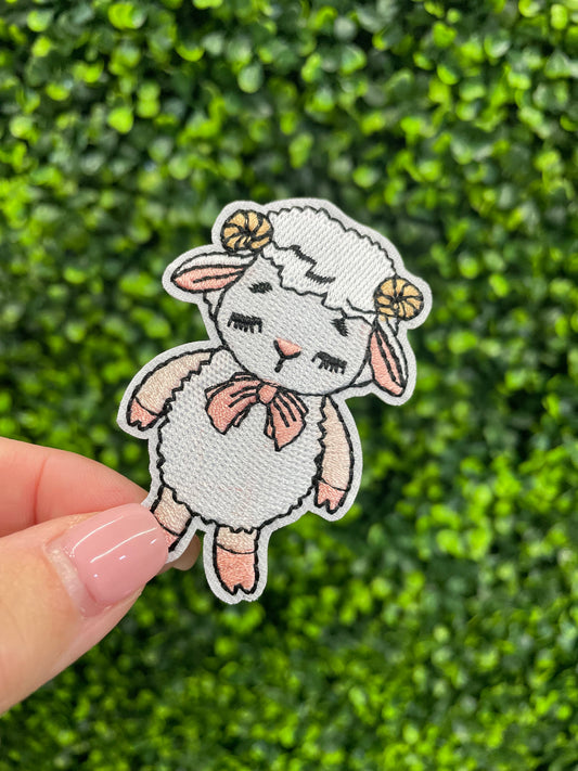 Patch of a cartoon lamb held against a green leafy background