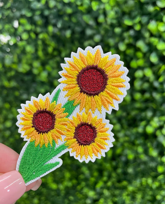 Three sunflower patch held against a green leafy background