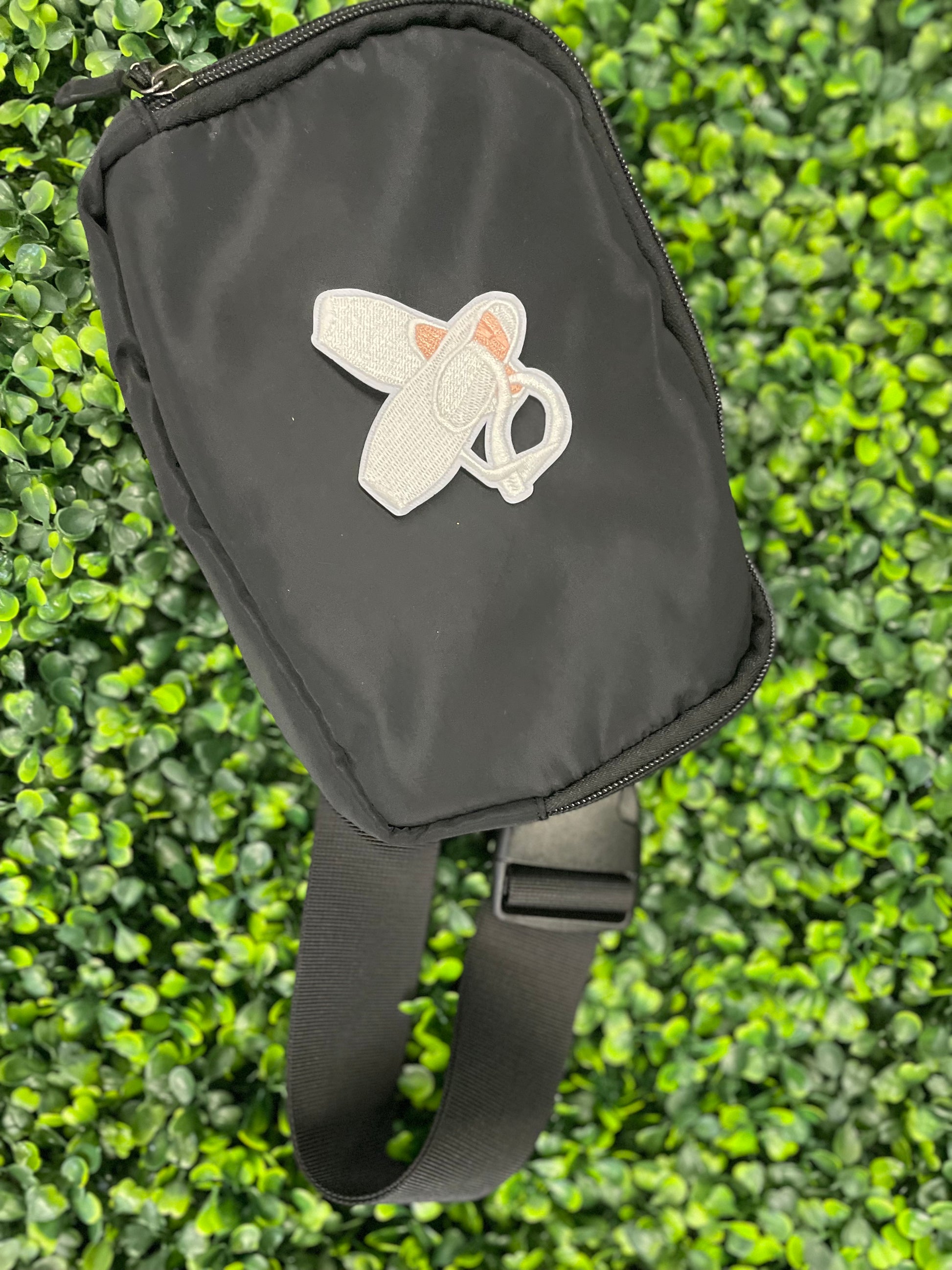 Embroidered patch of a pair of ballet slippers placed on a black shoulder bag