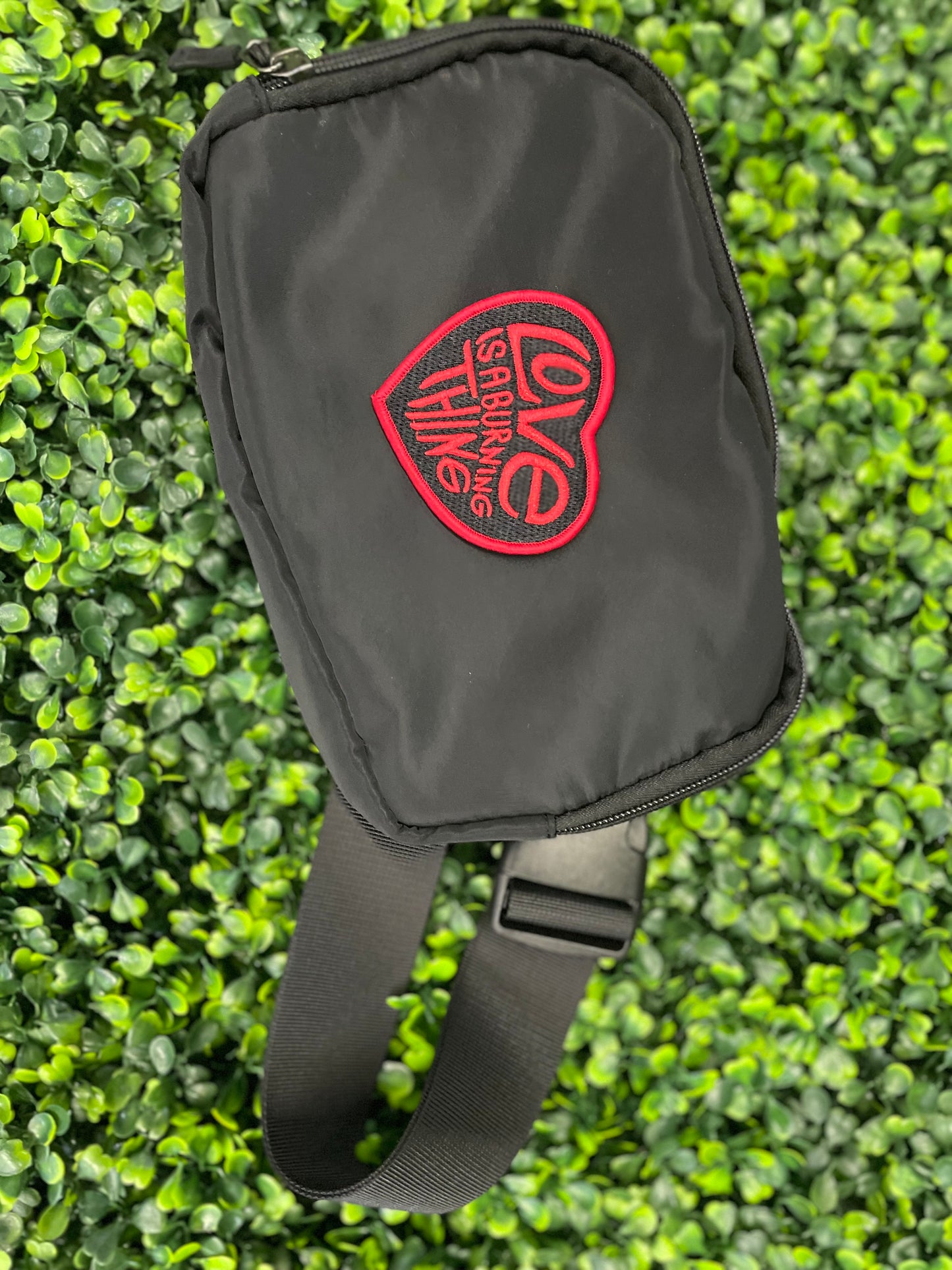 Heart-shaped patch with 'Love is a Burning Thing' text, placed on a black fanny pack