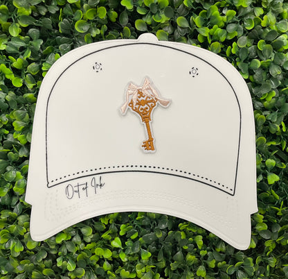 A patch in the shape of a vintage key with a gold bow, embroidery work, set on a white hat graphic