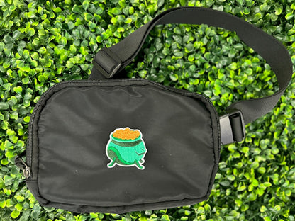 Green cauldron embroidered patch filled with gold coins and white border held on a black bag