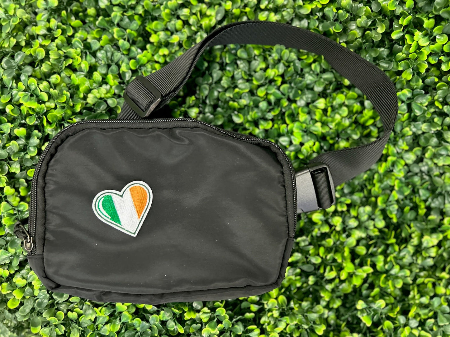 Heart shaped embroidered patch with Ireland flag colors green white and orange held on a black bag