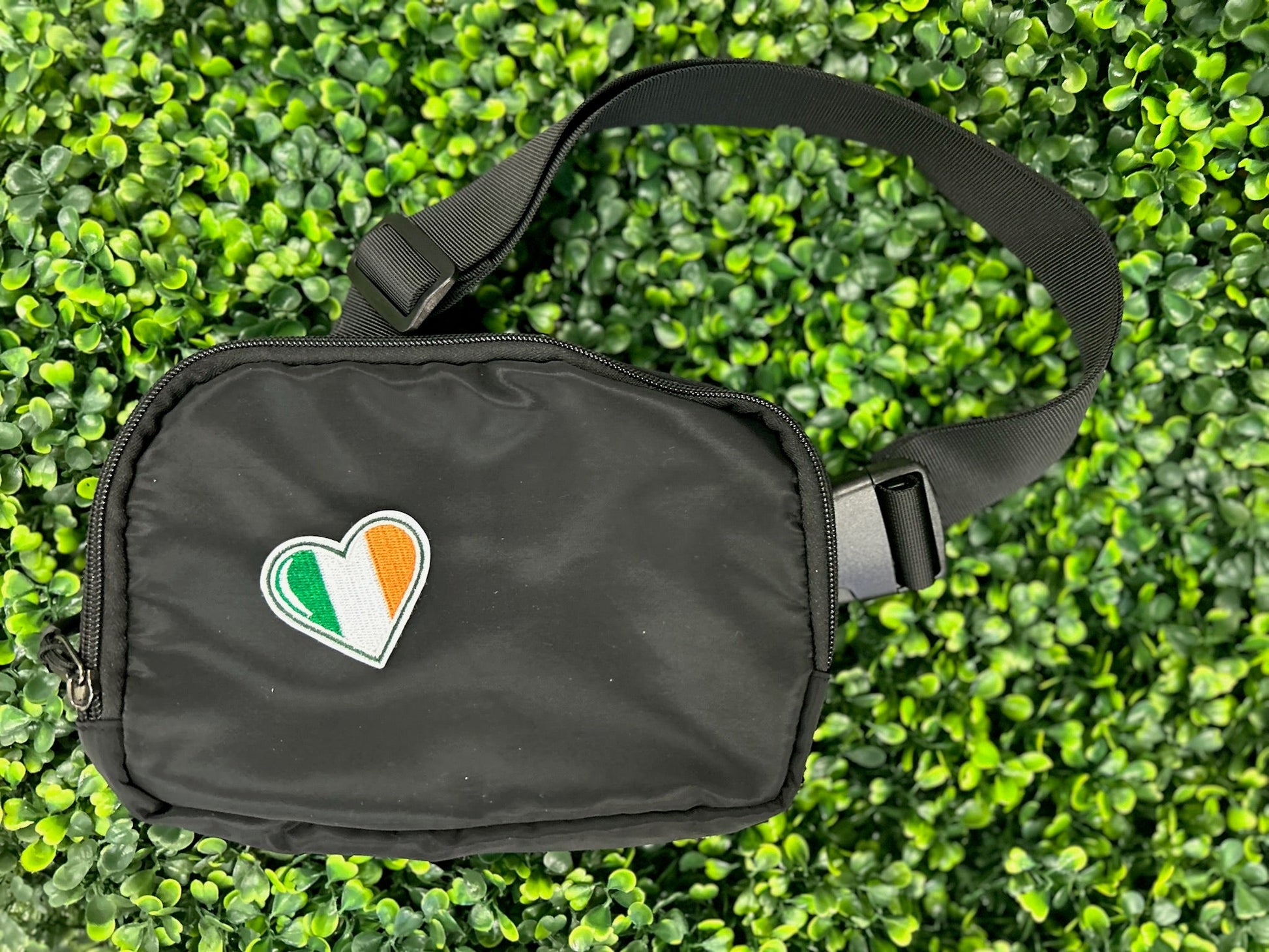 Heart shaped embroidered patch with Ireland flag colors green white and orange held on a black bag
