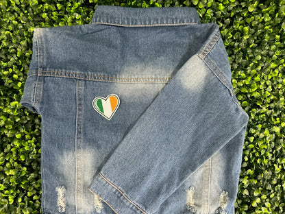 Heart shaped embroidered patch with Ireland flag colors green white and orange held on a children's denim jacket