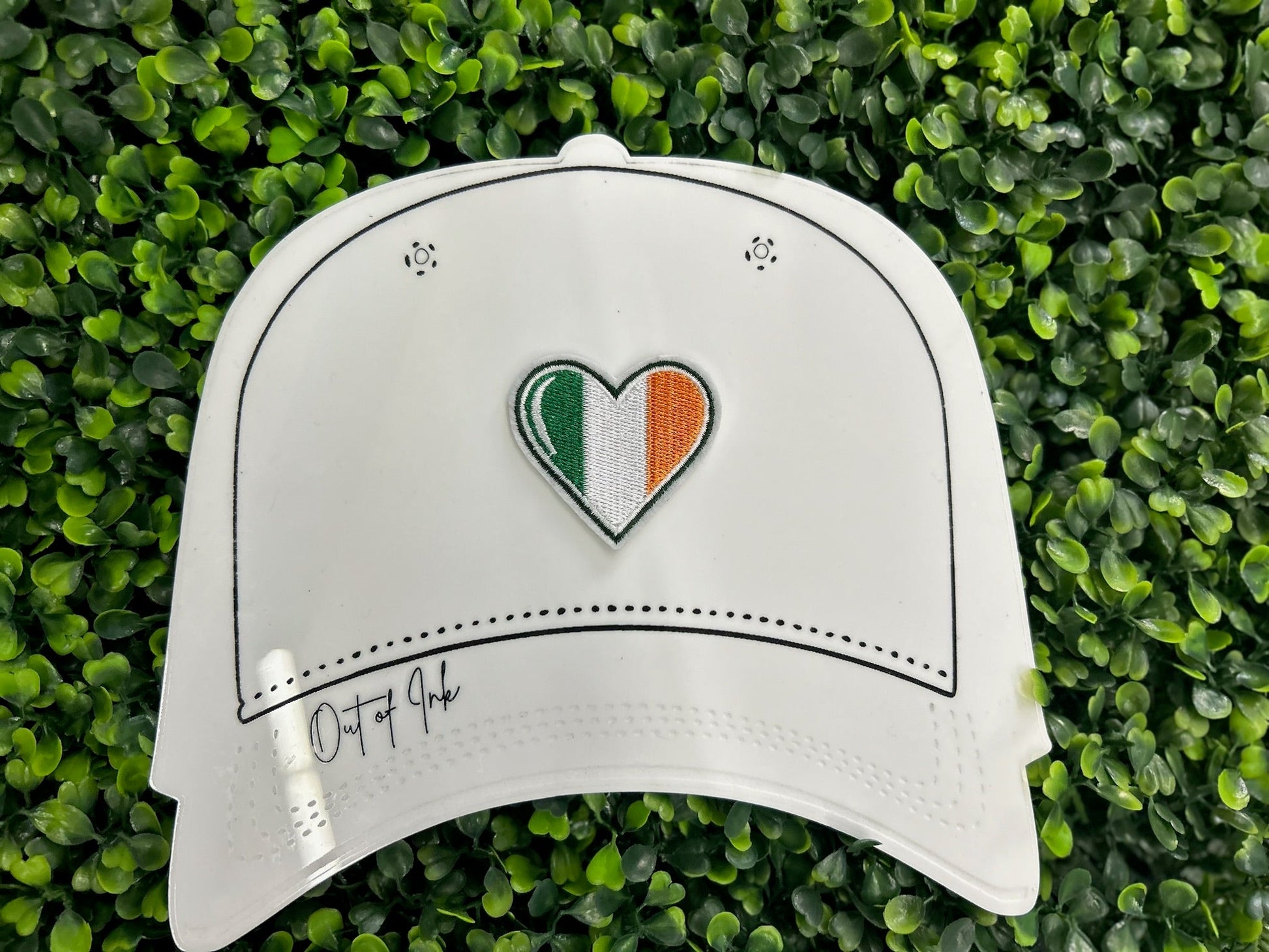 Heart shaped embroidered patch with Ireland flag colors green white and orange held on a white hat graphic