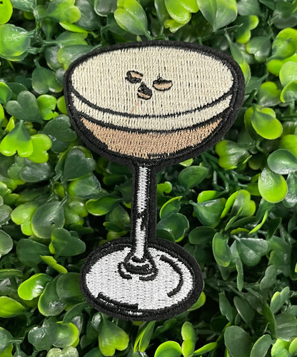 An embroidered martini glass depiction set on a green backdrop