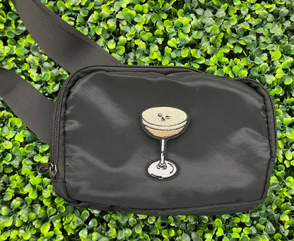An iron on embroidered martini glass depiction set on a black shoulder bag 