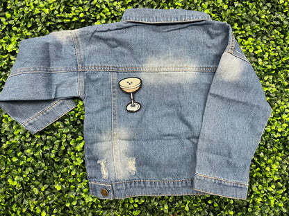 An iron on embroidered martini glass depiction set on a childs jean jacket