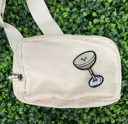 An iron on embroidered martini glass depiction set on a white shoulder bag