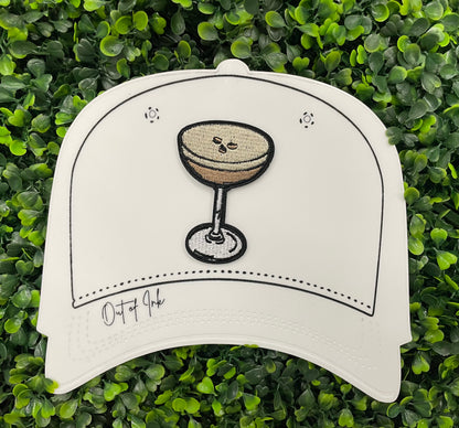 An iron on embroidered martini glass depiction set on a white hat