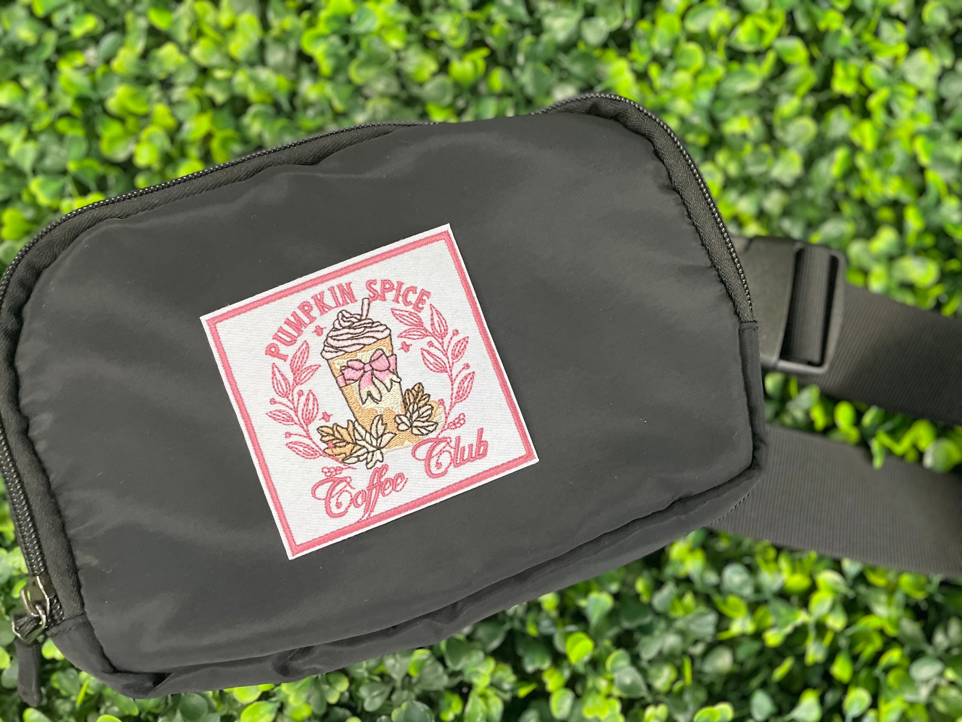Sticker with pumpkin spice latte design and the text "pumpkin spice coffee club" placed on a black fanny pack