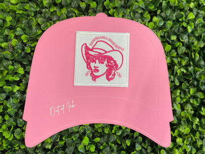 Embroidered patch with pink design and text "raising hell since birth" on a white background, placed on a pink hat graphic