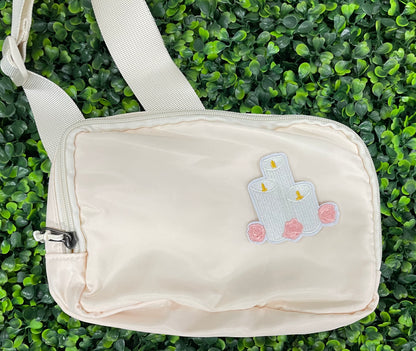 A patch with embroidered candles and roses in pink and yellow colors on a white background, placed on a white shoulder bag
