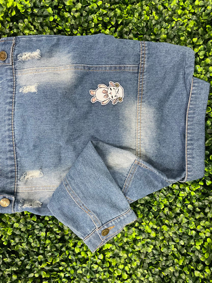 Patch of a cartoon lamb held against a children's denim jean-jacket